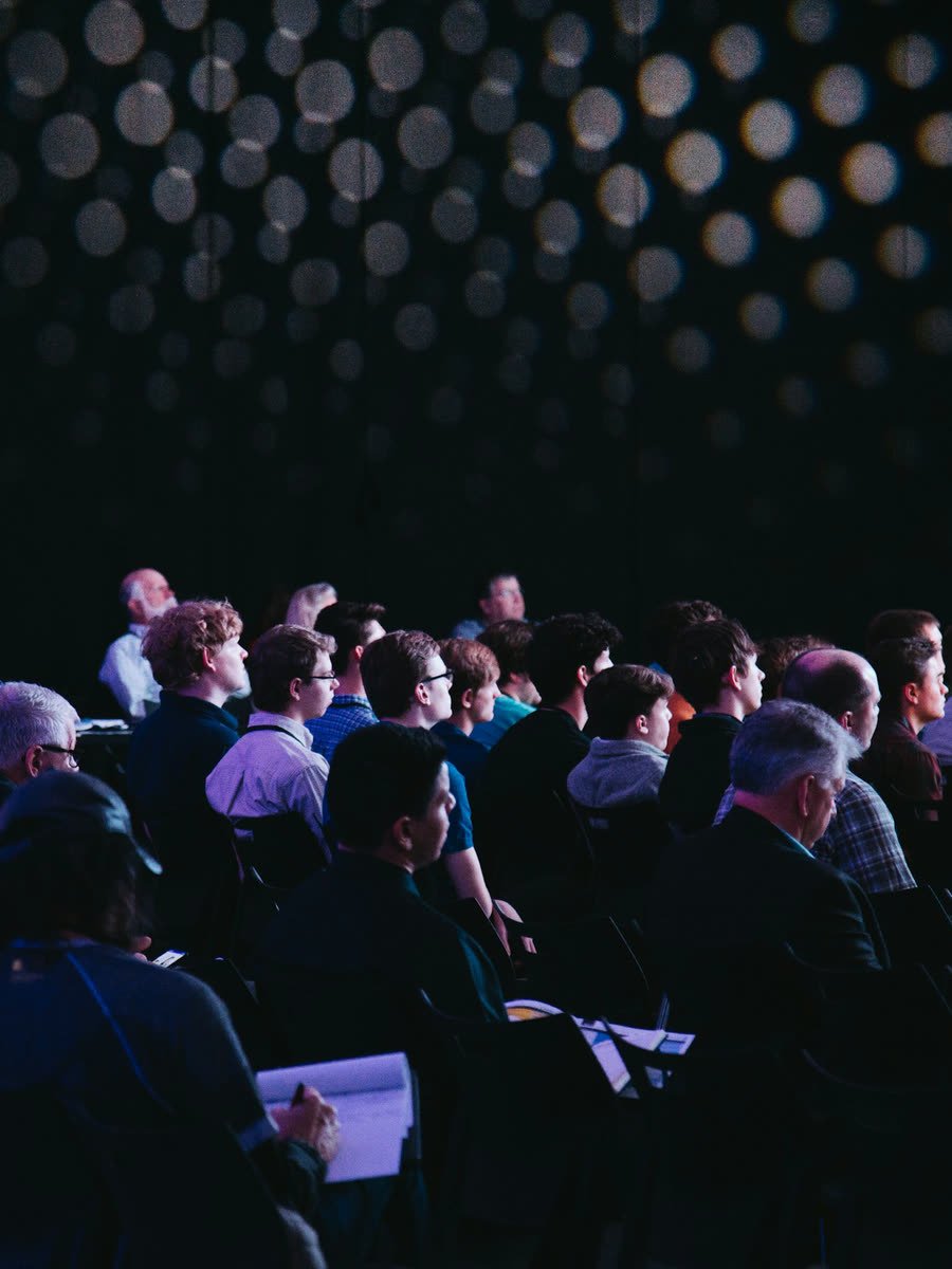 An audience seated in a darkened venue.