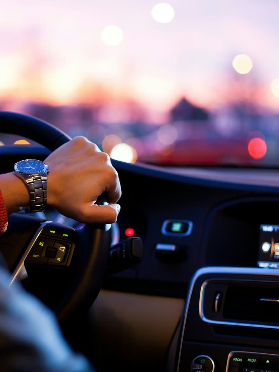 A protective driver at the wheel of a vehicle moving through a city at night.